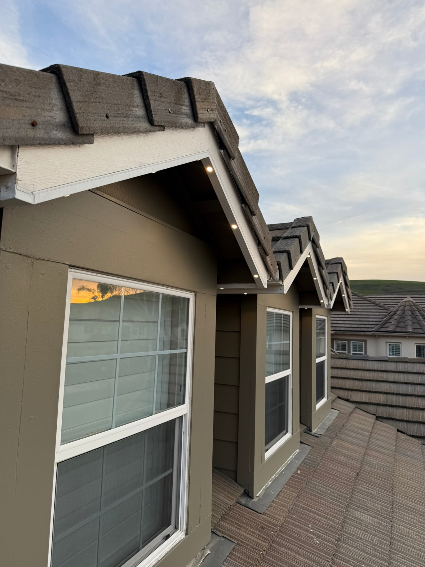 Govee puck lights recessed in a color-matched track under gable dormers glowing warm white