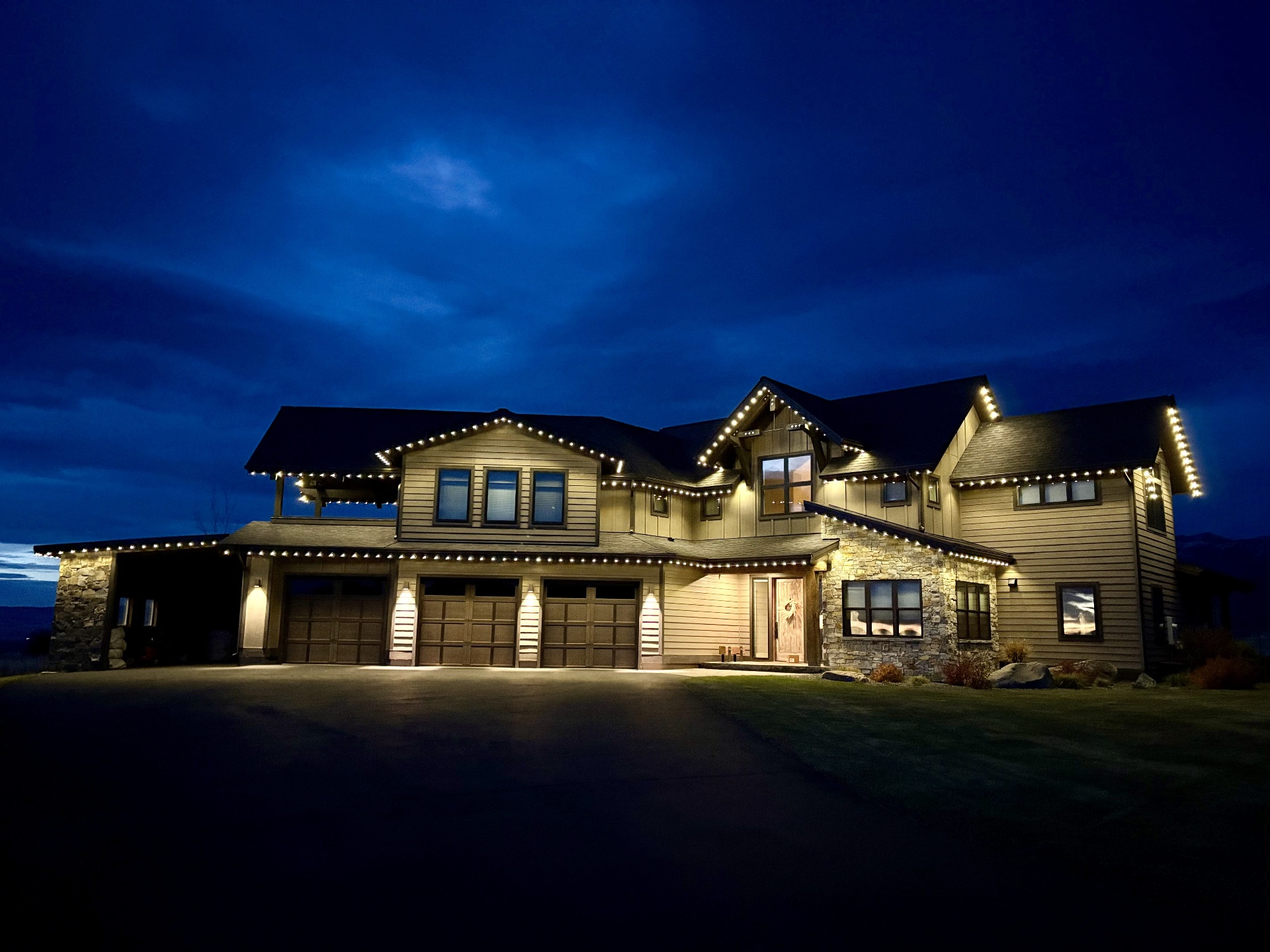 Large home at twilight lit with warm white permanent lighting along every roofline